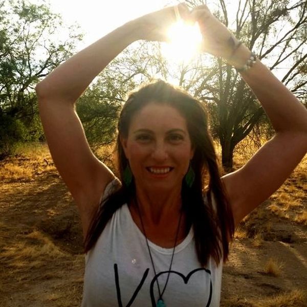 Woman making a heart shape with her hands against the sun.
