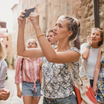 Ragazza che scatta una foto con amici in un vicolo.