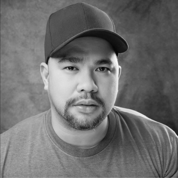 Close-up portrait of a man wearing a blue cap and gray shirt.
