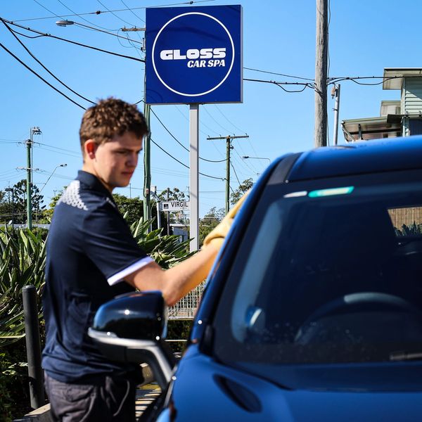 Young man cleaning a blue car at Gloss Car Spa.