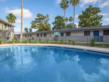 Outdoor swimming pool in a residential complex with palm trees.