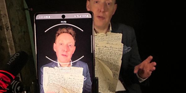 A man holding an old handwritten letter, captured on a smartphone screen.