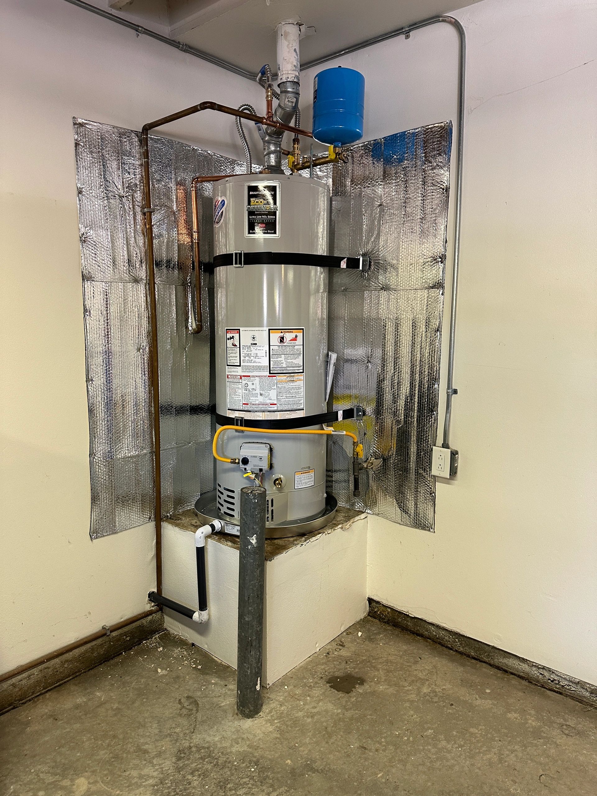 A water heater installed with insulation panels in a corner of a room.