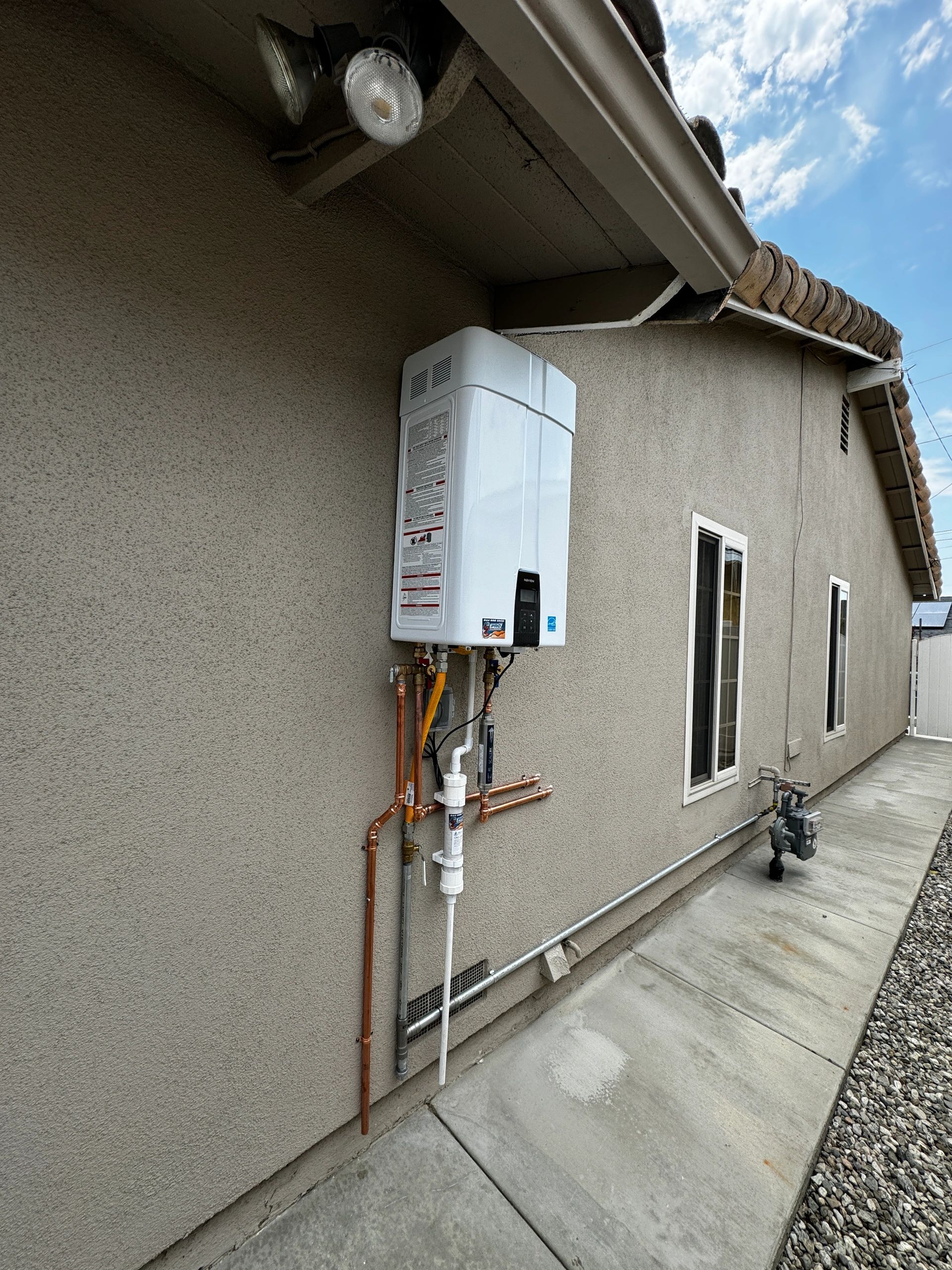 Tankless water heater installed on an exterior wall of a house.