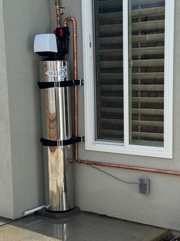 A shiny Halo 5 water softener system installed beside a window.