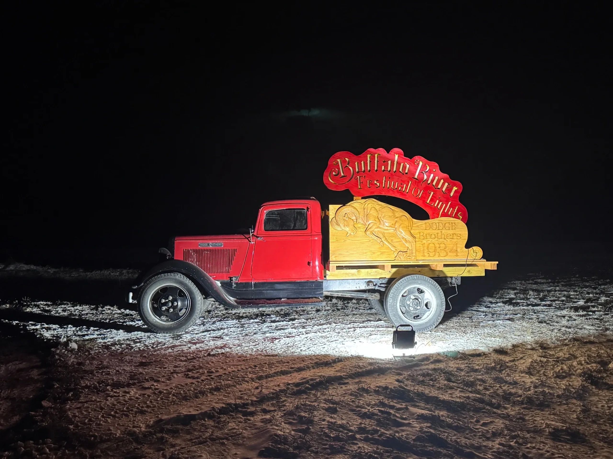 Vintage red truck displaying the Buffalo River Festival of Lights sign at night