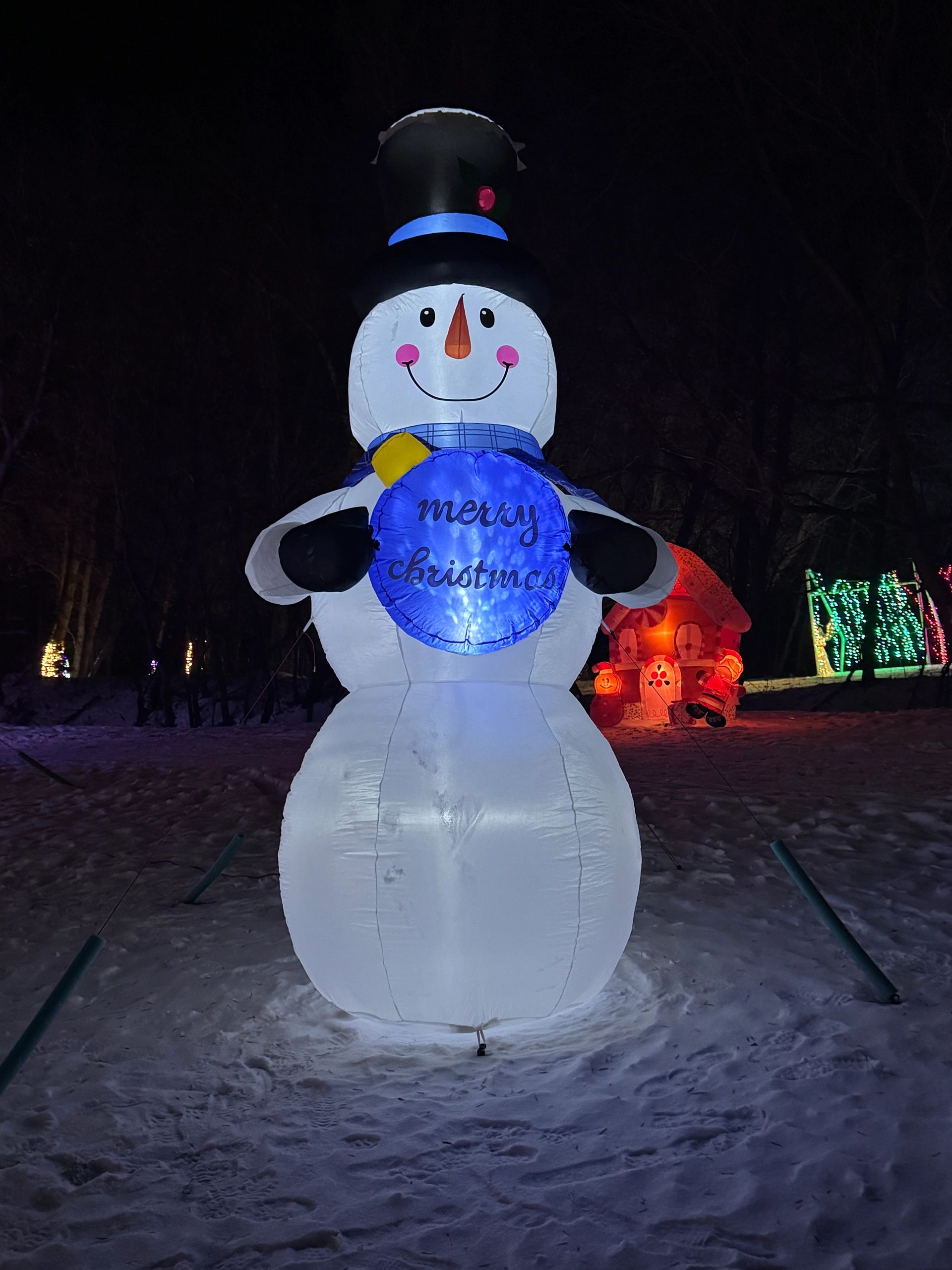 Giant illuminated snowman display along the snowy Festival of Lights walking path