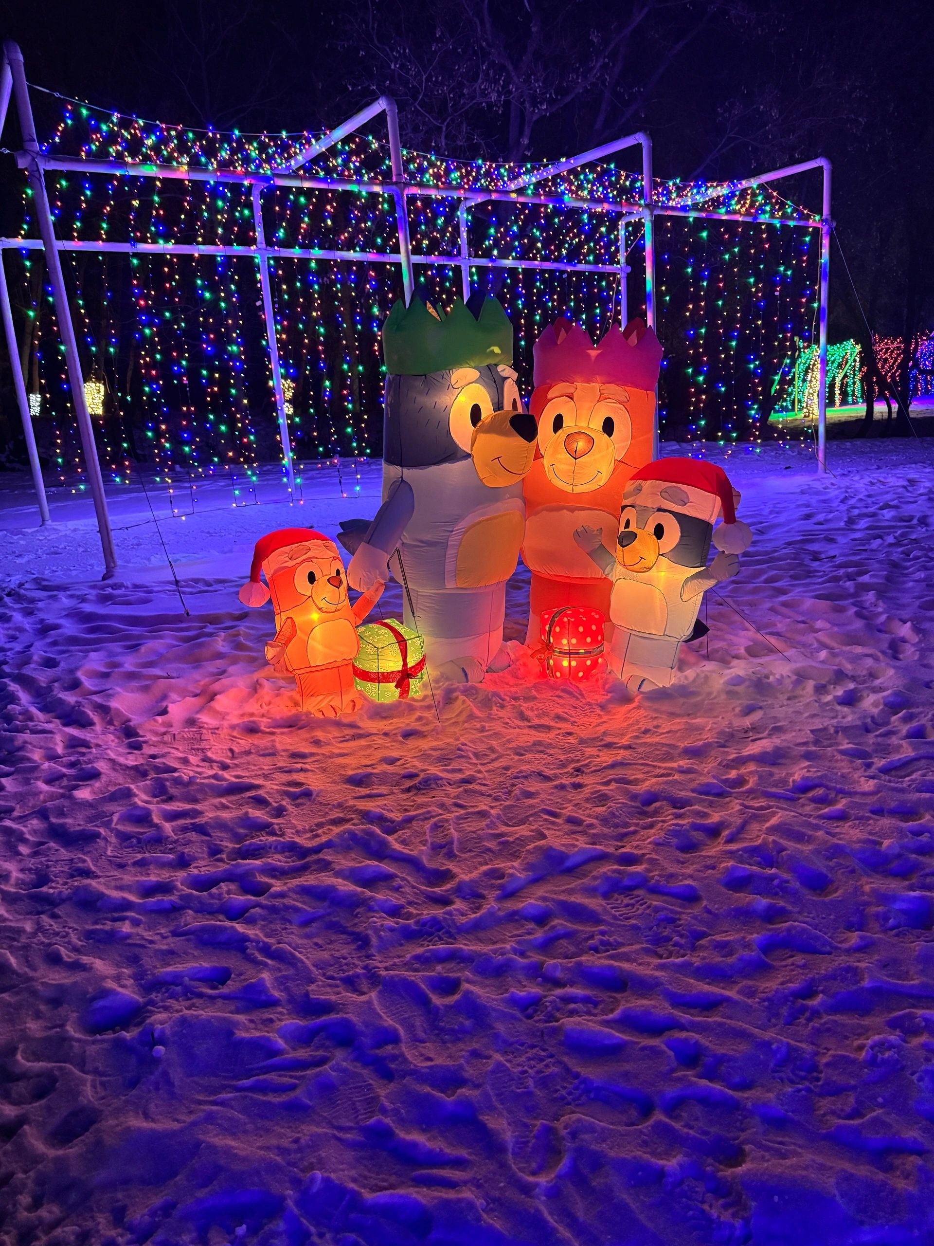Festive cartoon dog inflatables surrounded by colorful Christmas lights and snow