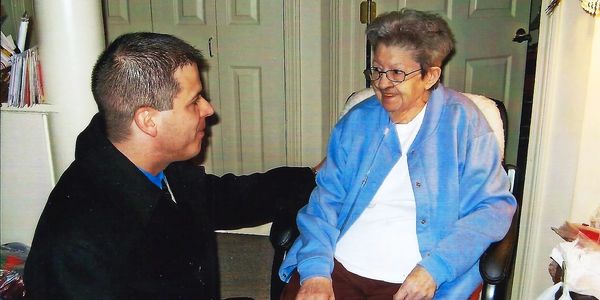 Woman on oxygen, smiling woman, man kneeling, politician, blue sweater, caregiving