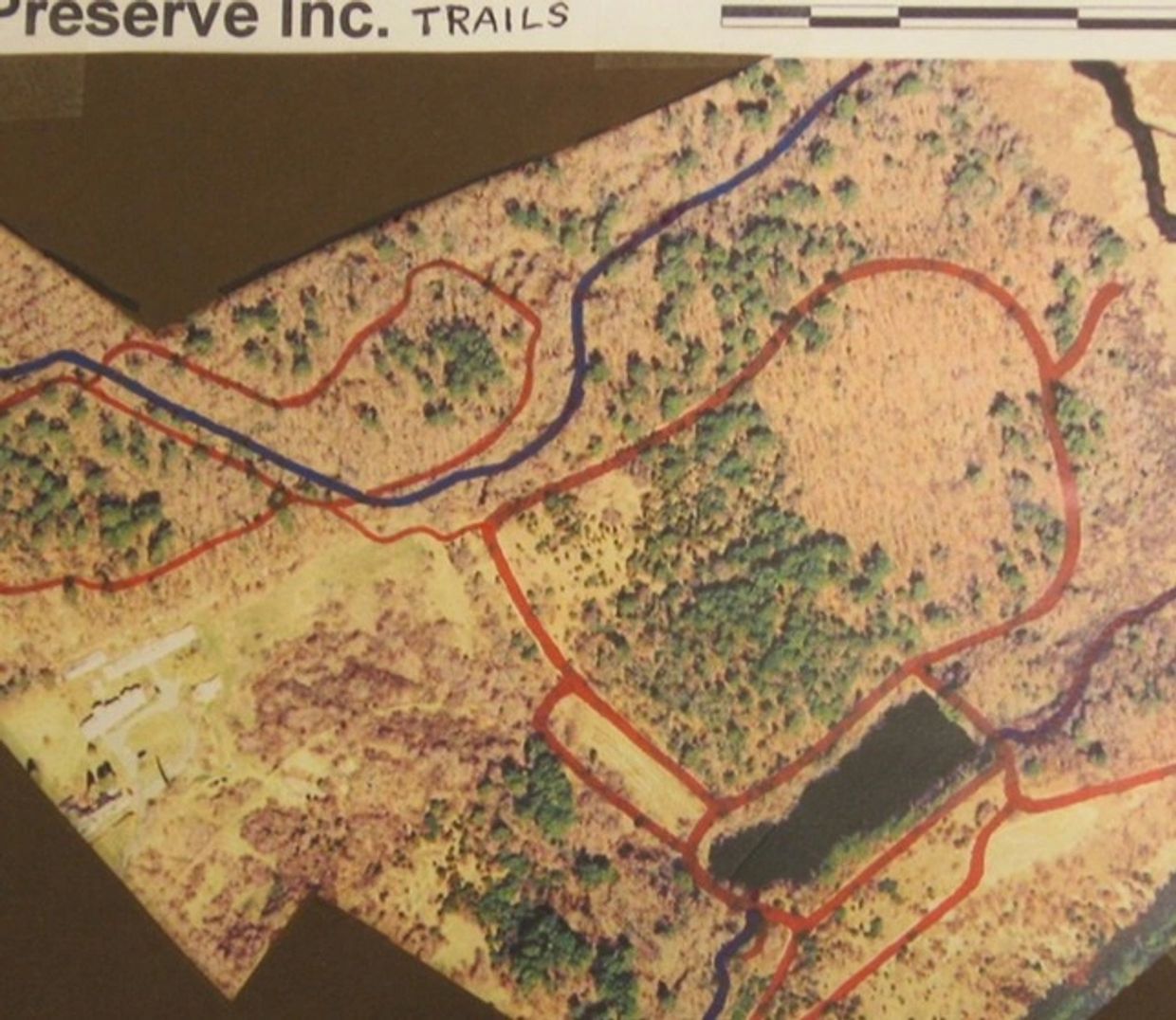 Aerial view of a nature preserve with marked trails and a pond.