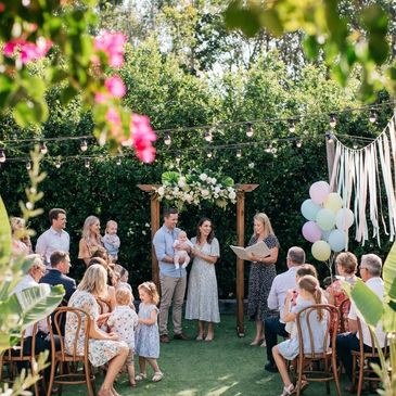 Outdoor family gathering with a floral arch and pastel balloons, for baby naming day, led by a naming ceremony celebrant, 