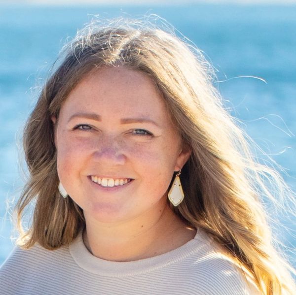 Smiling woman with long hair by the sea.
