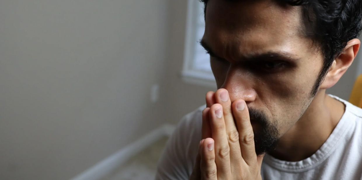 Man with anxiety holding hands to face