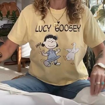 Person wearing a yellow "Lucy Goosey" Peanuts cartoon T-shirt.