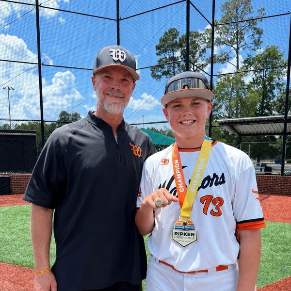 Baseball coach and player celebrating victory with medals.