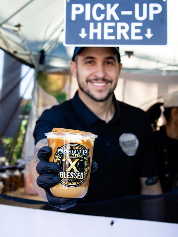 Barista holding iced coffee at pick-up window.