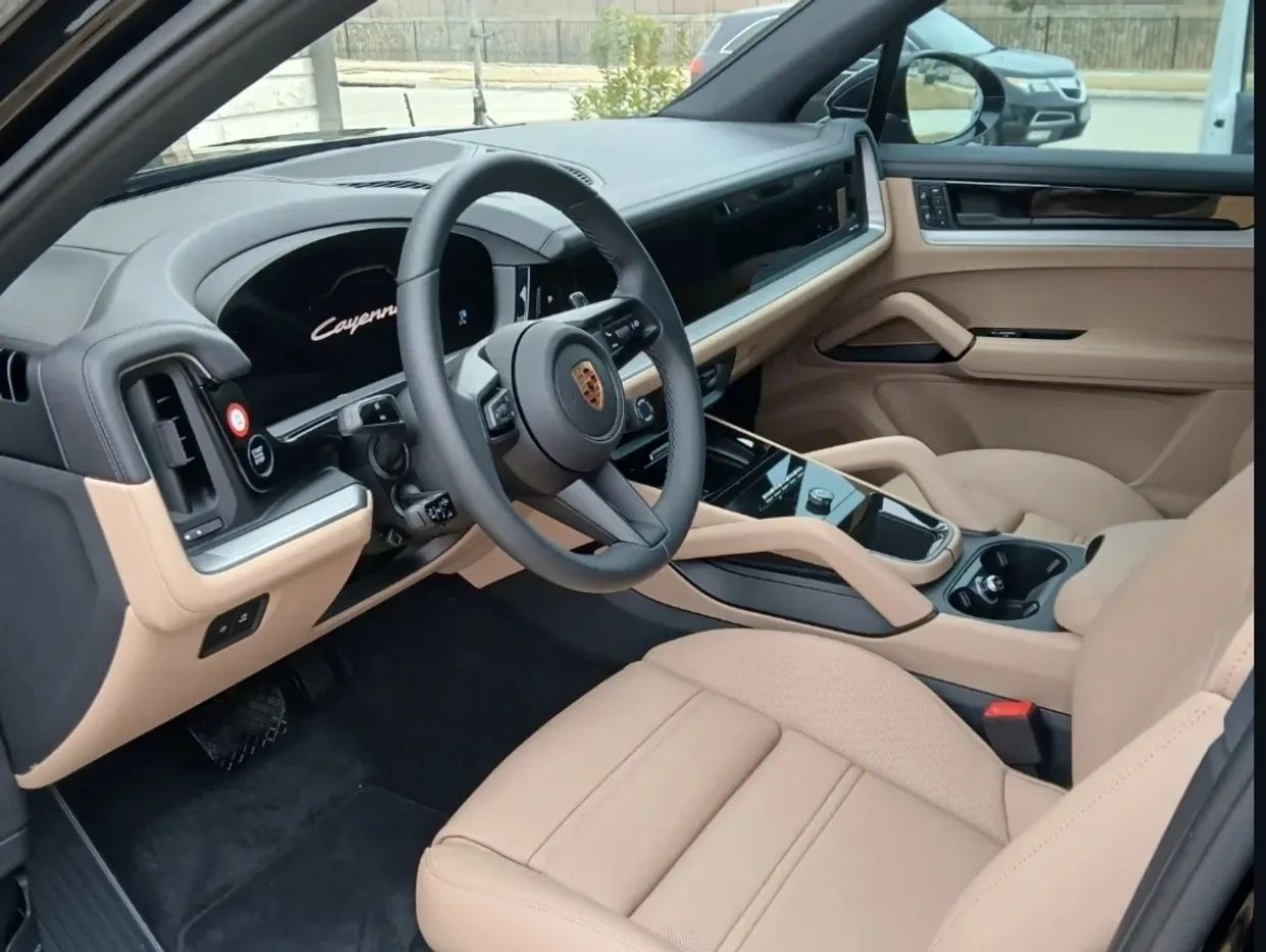 Luxury beige interior of a Porsche Cayenne with modern dashboard and steering wheel.