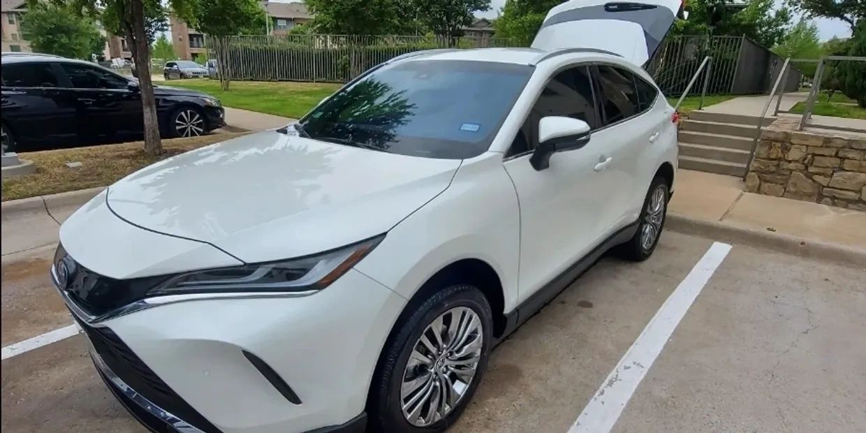White modern crossover SUV parked with trunk open in a residential area.
