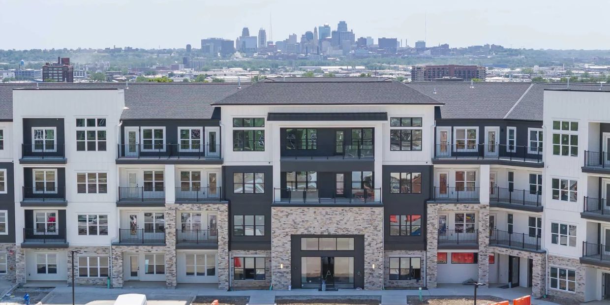 Modern apartment building with city skyline in background.