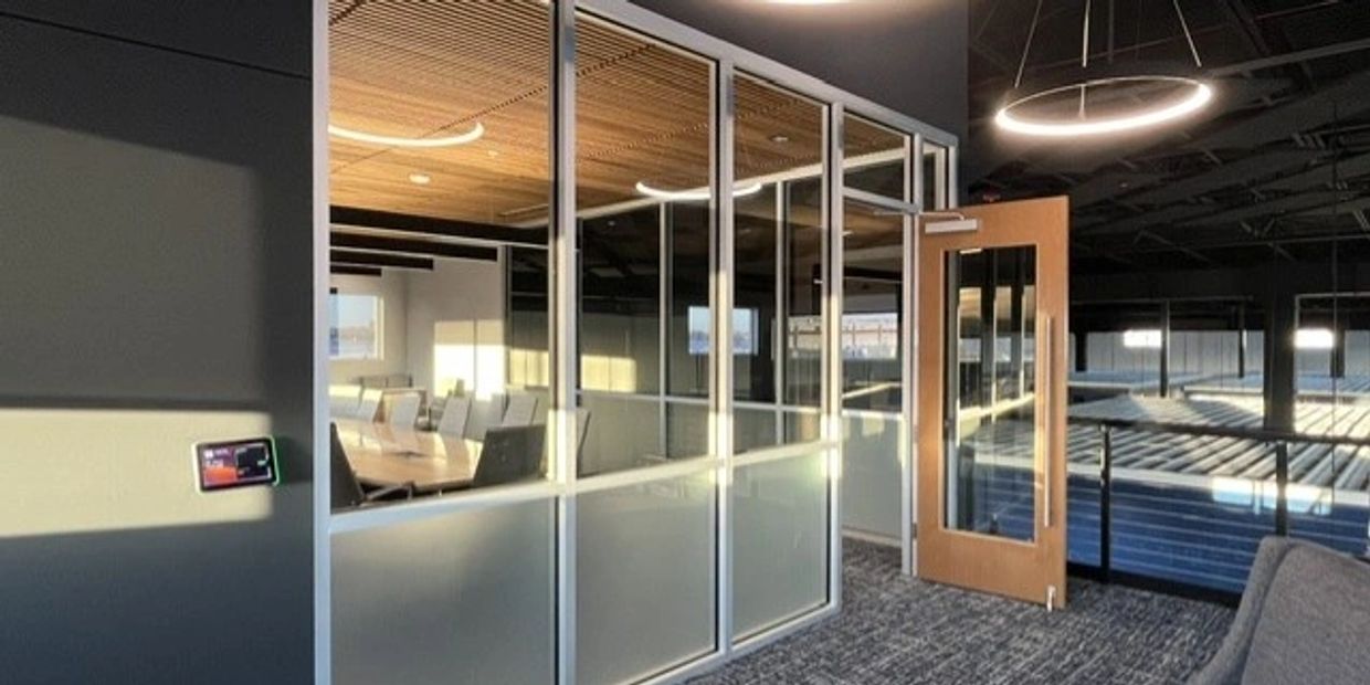 Modern office meeting room with glass walls and wooden door.