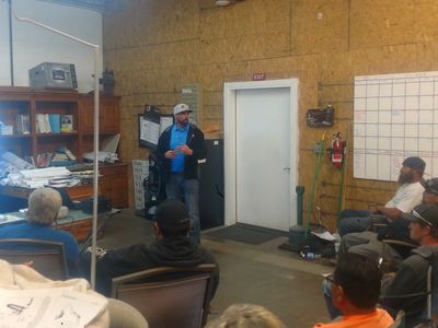 A man gives a presentation to a seated group in a workshop or classroom setting.