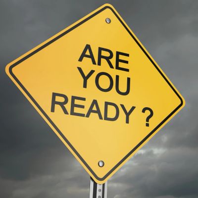 Yellow diamond-shaped sign reading 'ARE YOU READY?' against a cloudy sky.