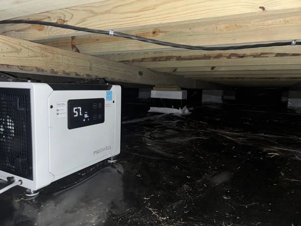 A moisture control device installed in a crawl space under a wooden floor.