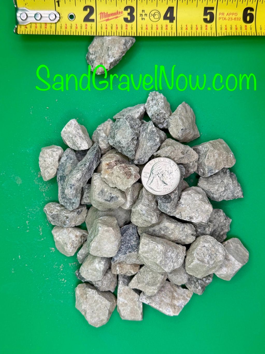 Pile of gravel with a quarter and measuring tape for scale.