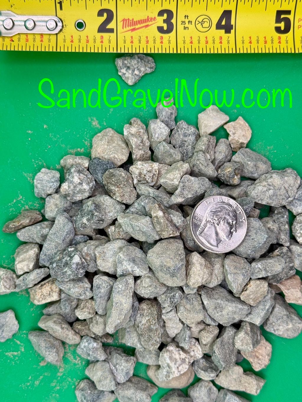 Gray gravel pieces next to a quarter and measuring tape for size reference.