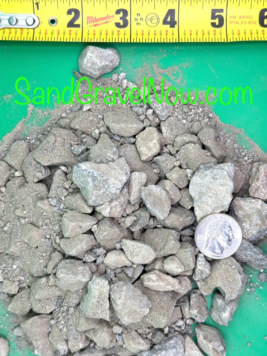 A pile of gravel with a measuring tape and a quarter for scale.