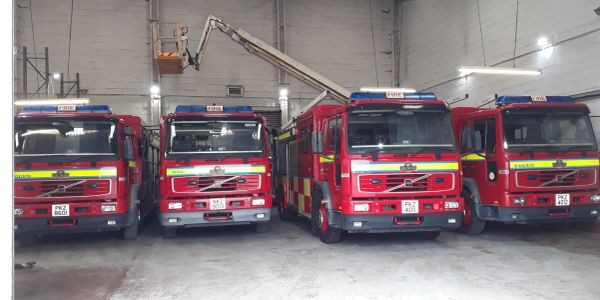 Four red fire trucks parked inside a fire station.