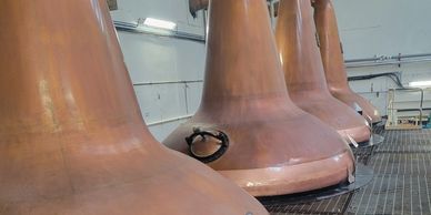 Large copper stills in a distillery lined up in a row.