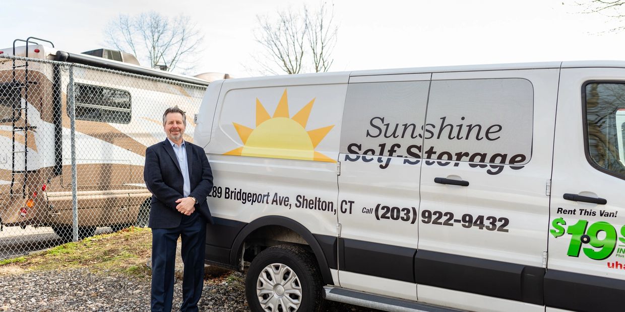 A man in a suit standing in front of a van