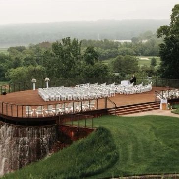 Outdoor wedding setup on a deck with waterfall view.