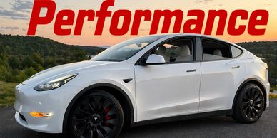 White Tesla Model Y with 'Performance' text at sunset.