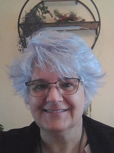 Smiling woman with glasses and short, gray hair.