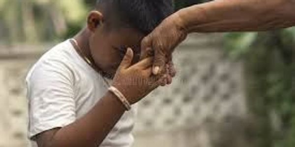 A child respectfully touches an elder's hand in a traditional gesture.