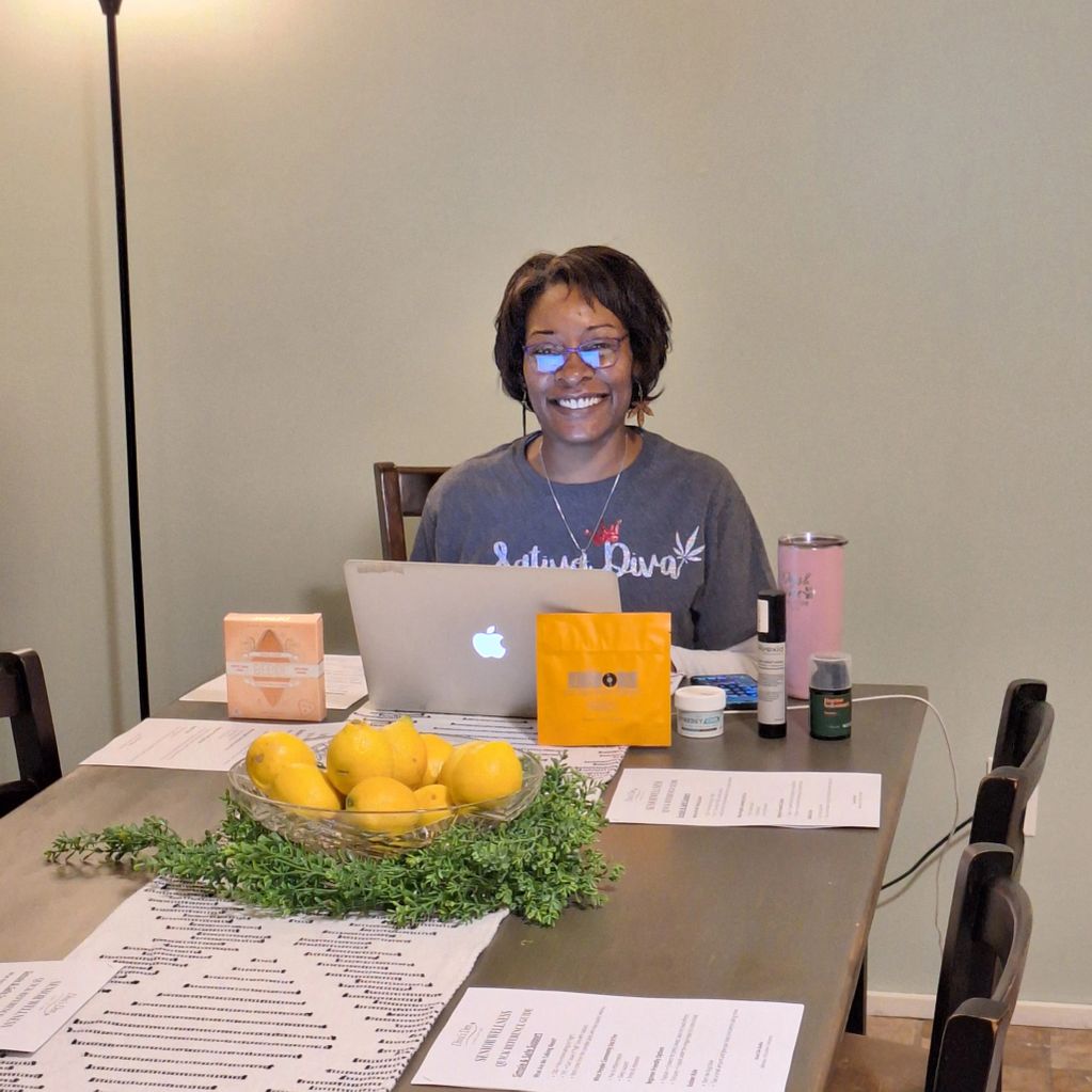 Smiling woman working on a laptop at a table with lemons and skincare products.