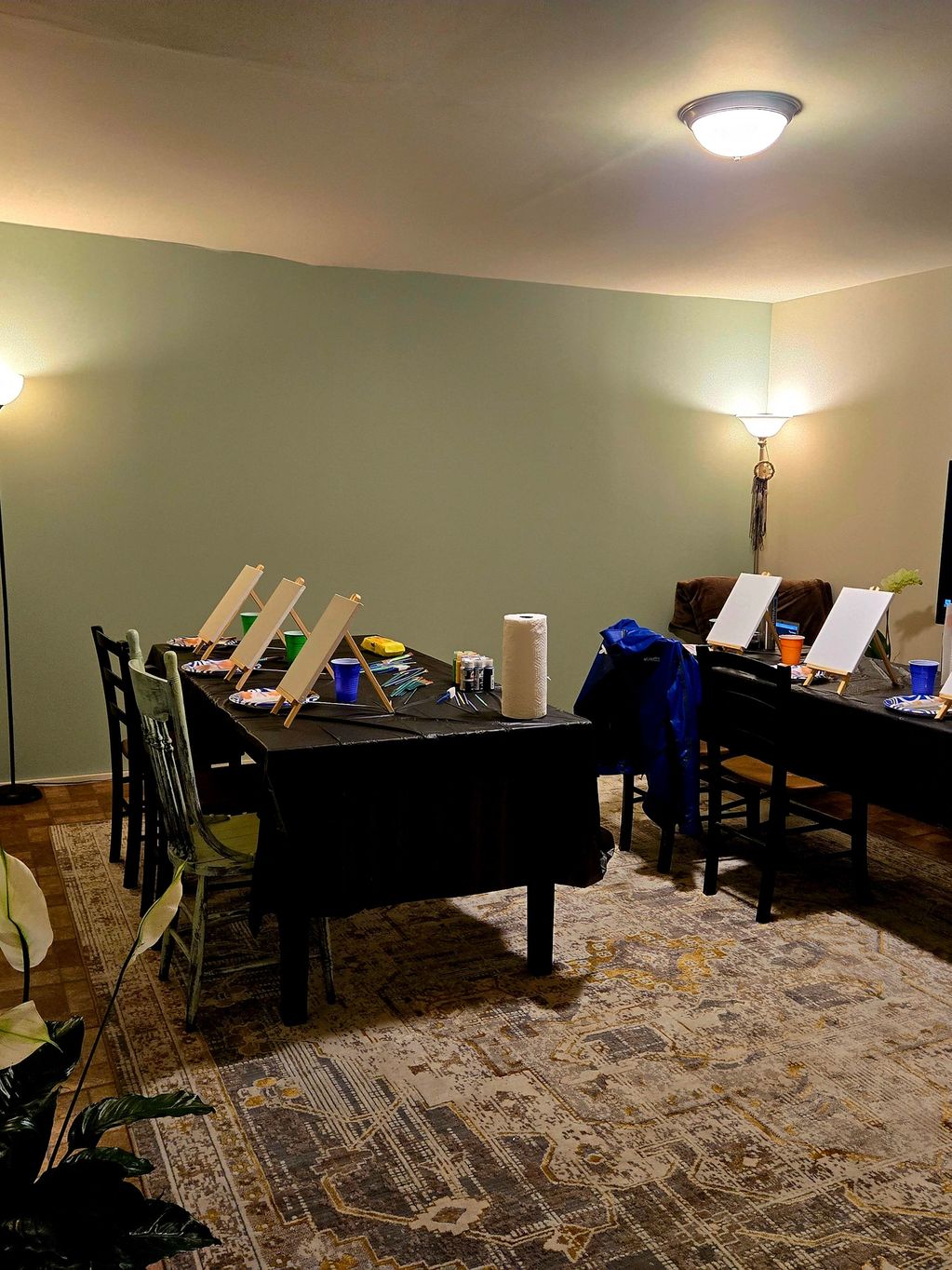 Room set up for a group painting session with easels and art supplies.