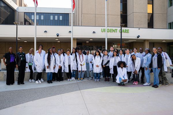 Group of diverse medical professionals posing outside an urgent care center.