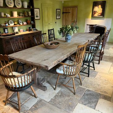 Rustic dining room with a long wooden table and mismatched chairs.