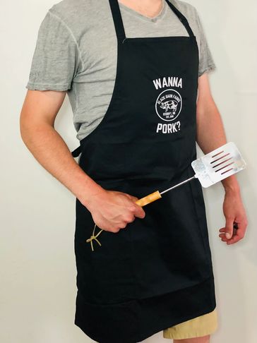 Model wearing BBQ apron with Black Barn Farms' logo and WANNA PORK tagline