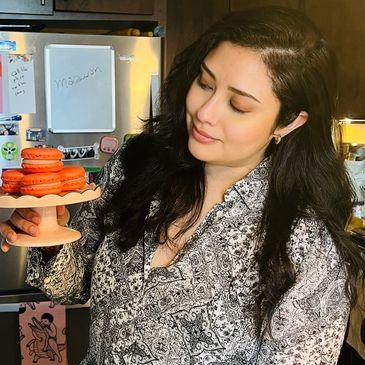 Woman holding a plate of orange macarons.