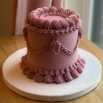 Elegant mauve decorated cake on white board.
