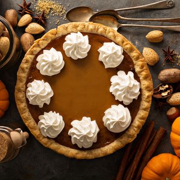 pumpkin pie with eight puffs of whipped cream decoratively placed in a circle on top of the pie
