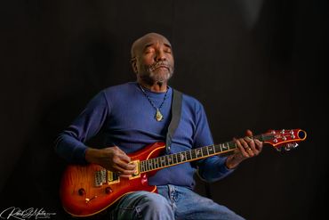 Man playing electric guitar with eyes closed, immersed in music.