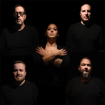 Five people in black clothing posing against a dark background.