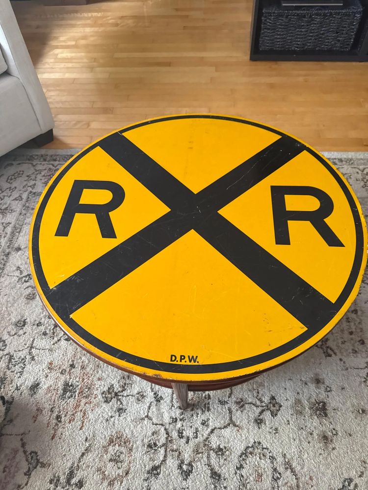 A round yellow table with a railroad crossing sign design.