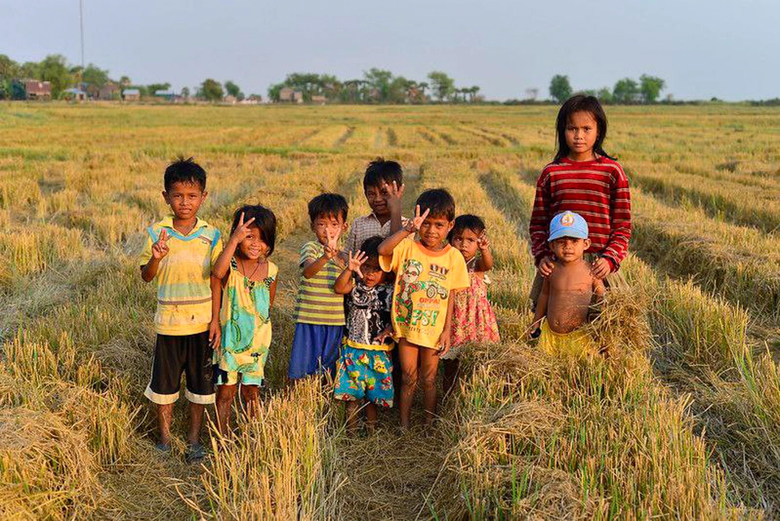 A group of children posing and making peace signs in a harvested field in Prey Veng provice.