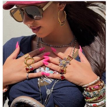 Woman with multiple rings, bracelets, and sunglasses.